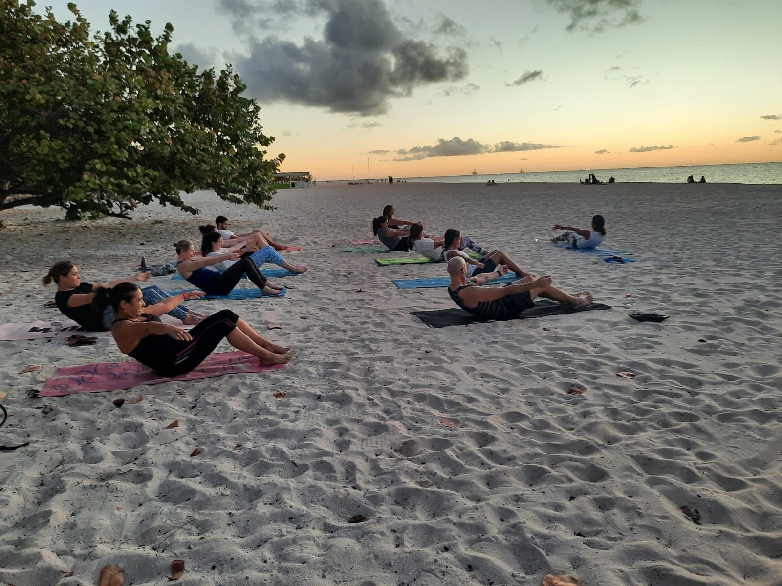 A beach yoga class flowing together on Eagle Beach at golden sunset