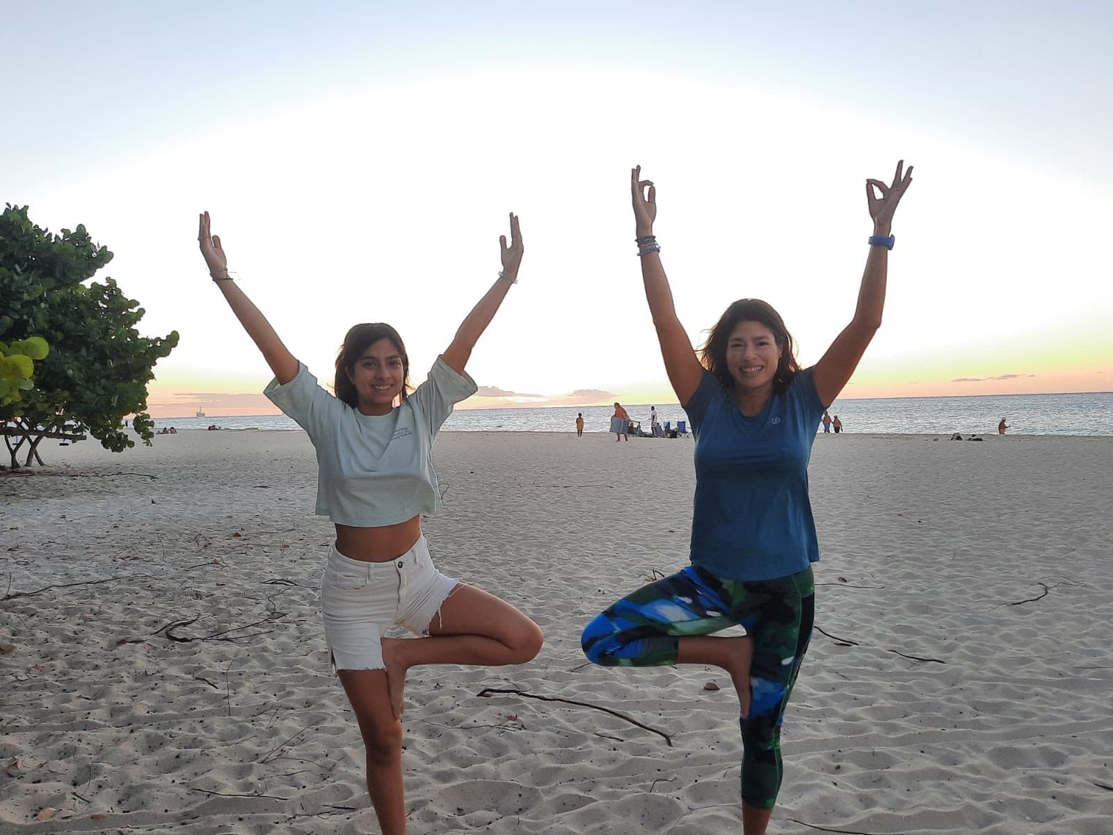 Two guests laughing with their arms raised into the sunset light