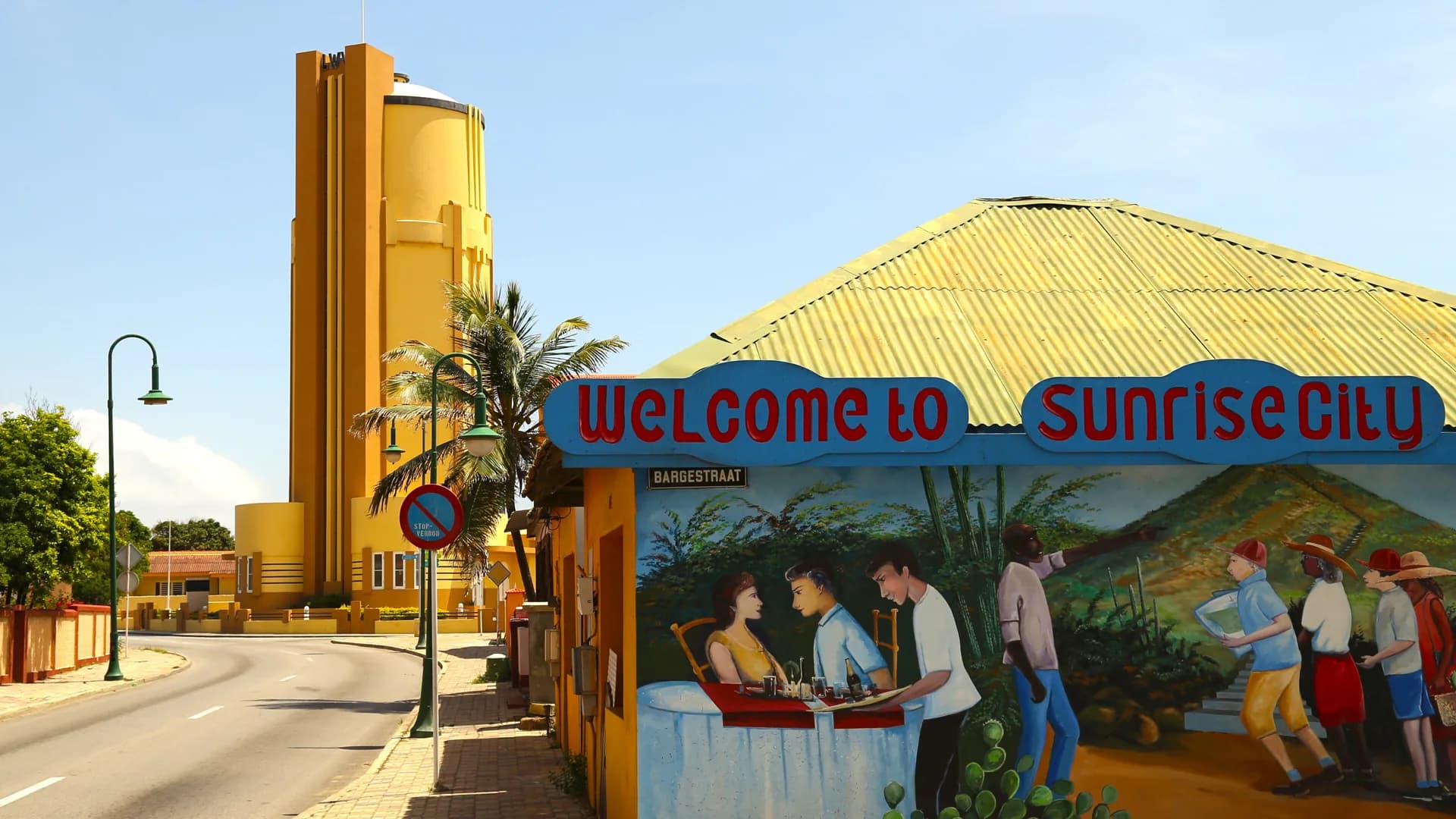 The Welcome to Sunrise City mural and yellow water tower in San Nicolas, Aruba