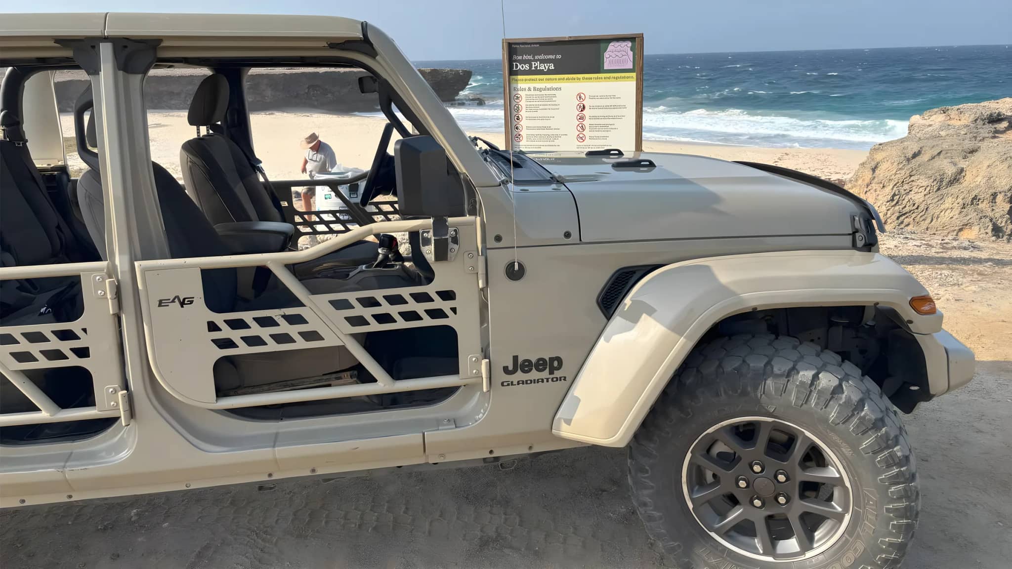 An open-air Jeep parked above the surf on the north coast of Aruba