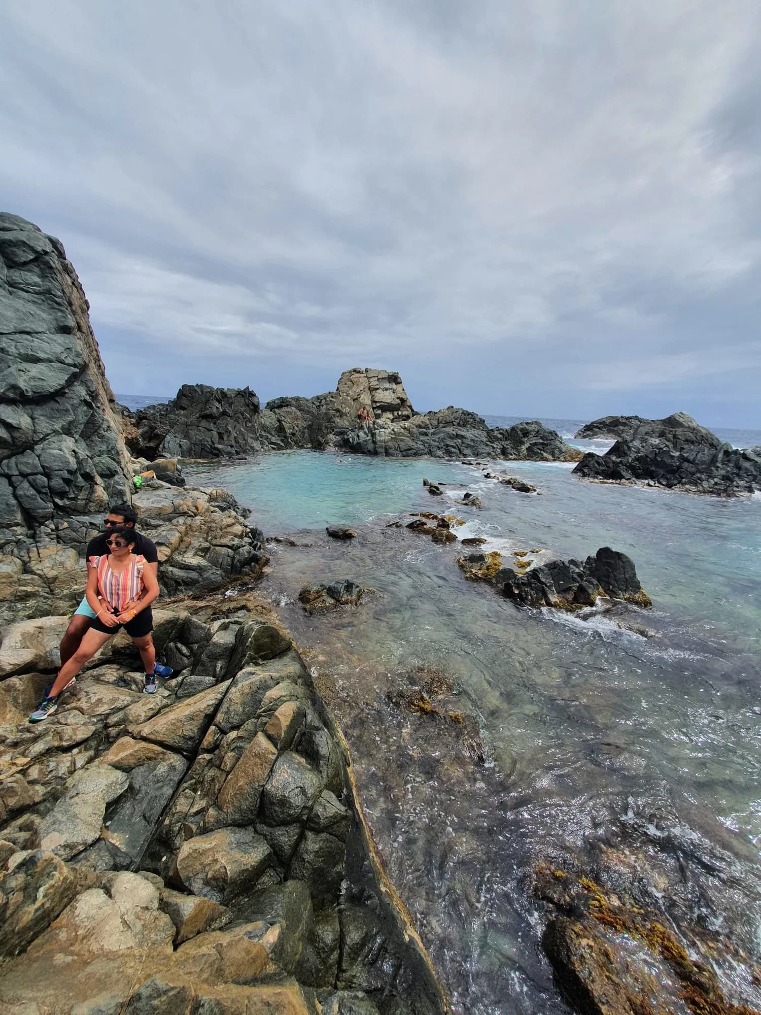 A guest sitting on the volcanic rocks beside the Natural Pool