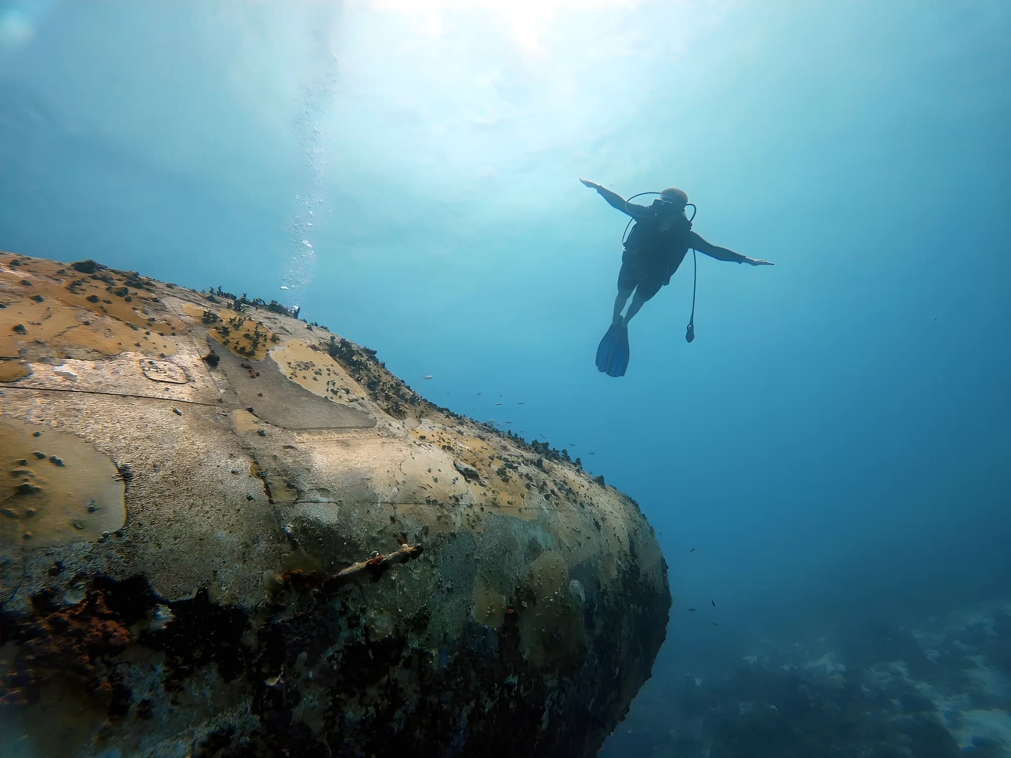 A diver hovering above the hull of a wreck on the Aruba south coast
