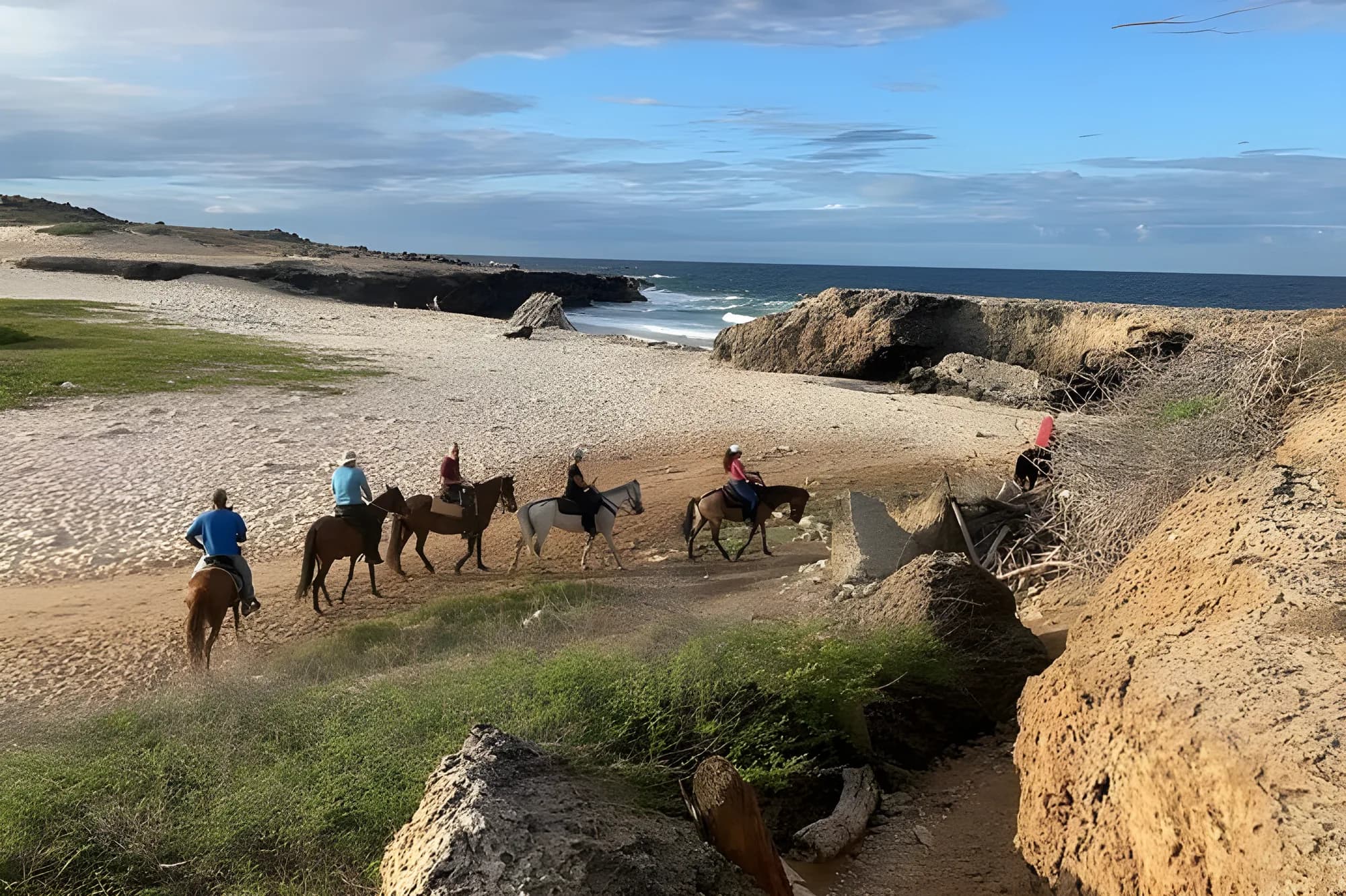 Riders on horseback on a rocky trail above the north coast of Aruba