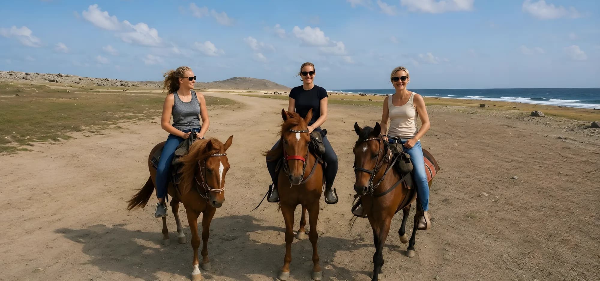 Three riders on horseback on a dirt road through the Aruban countryside