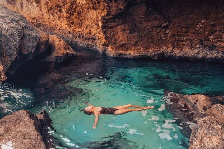 A guest floating alone in the Conchi natural pool at first light