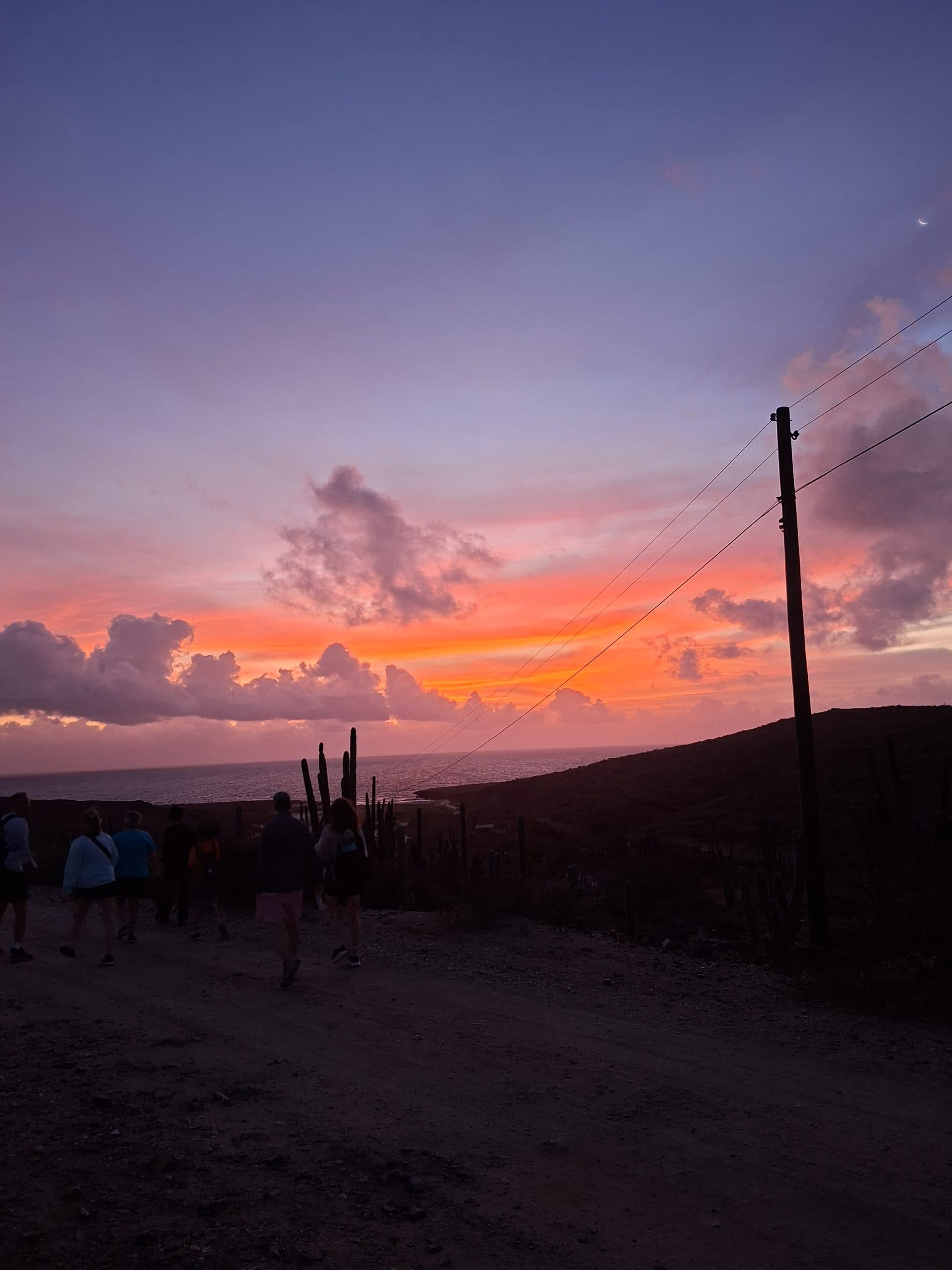 Hikers on the trail under a glowing dawn sky in Aruba