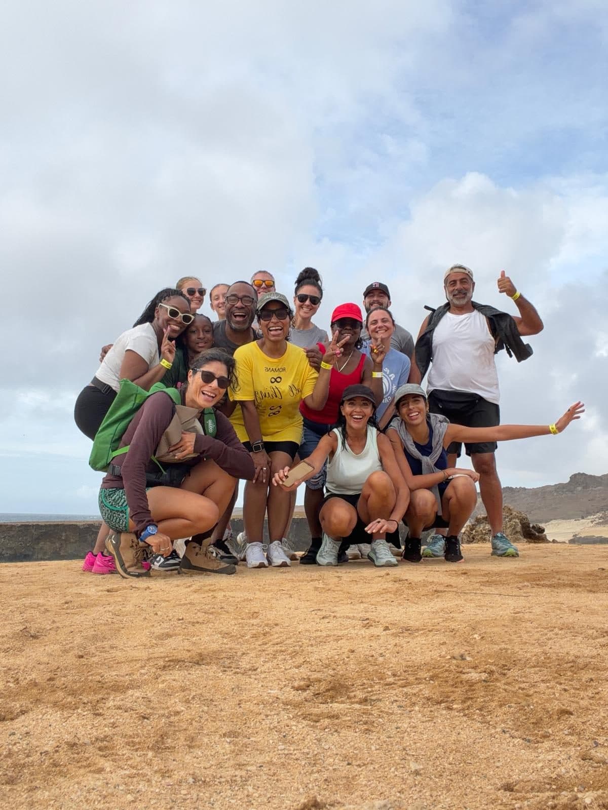 A beaming hiking group posing together on the sunrise trail