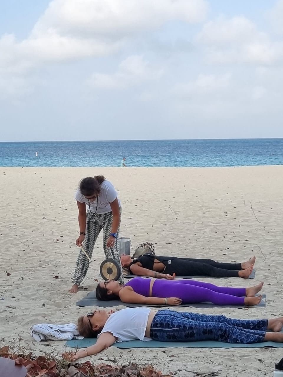 The instructor playing a drum over resting guests on the open beach