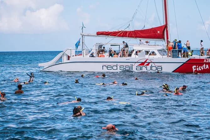 Snorkelers beside the red-and-white catamaran used by the Antilla snorkel cruise operator